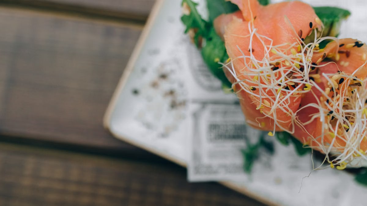 Close-up of fresh salmon sashimi garnished with sprouts, showcasing vibrant colors.